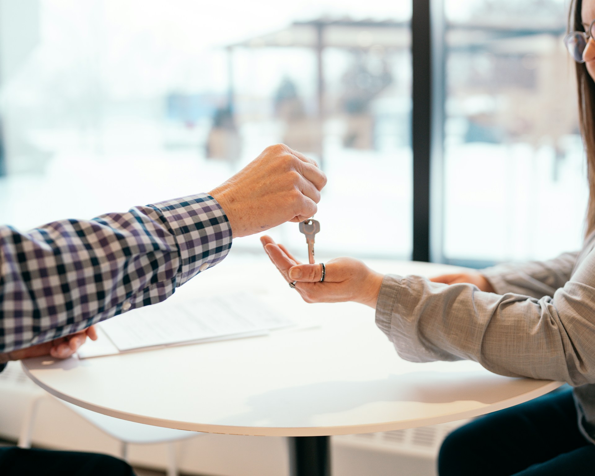 a man handing a key over to a woman sitting a table