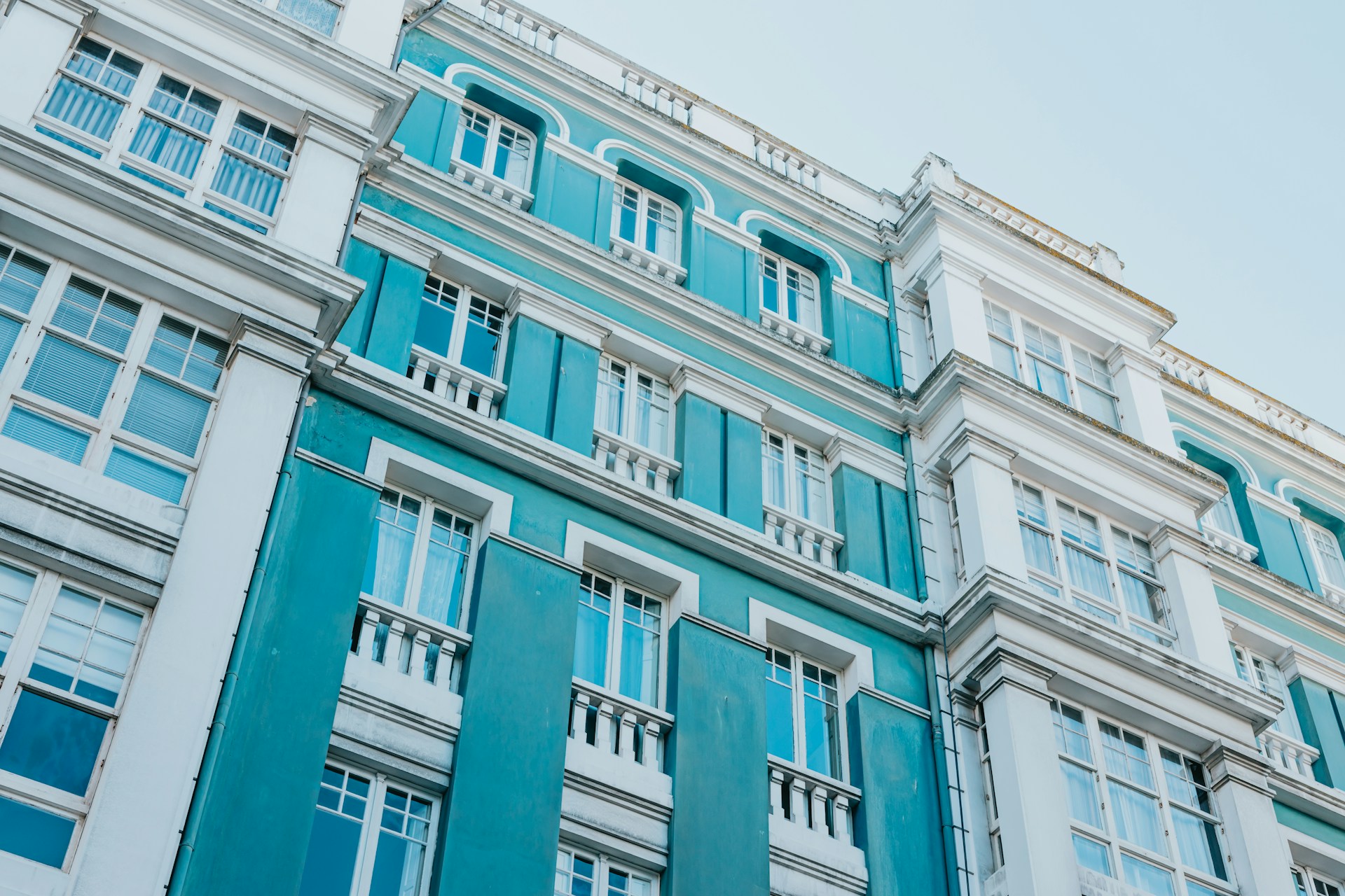 Street-level view looking up the side of a bright blue and white condo building, representing buying a condo in BC