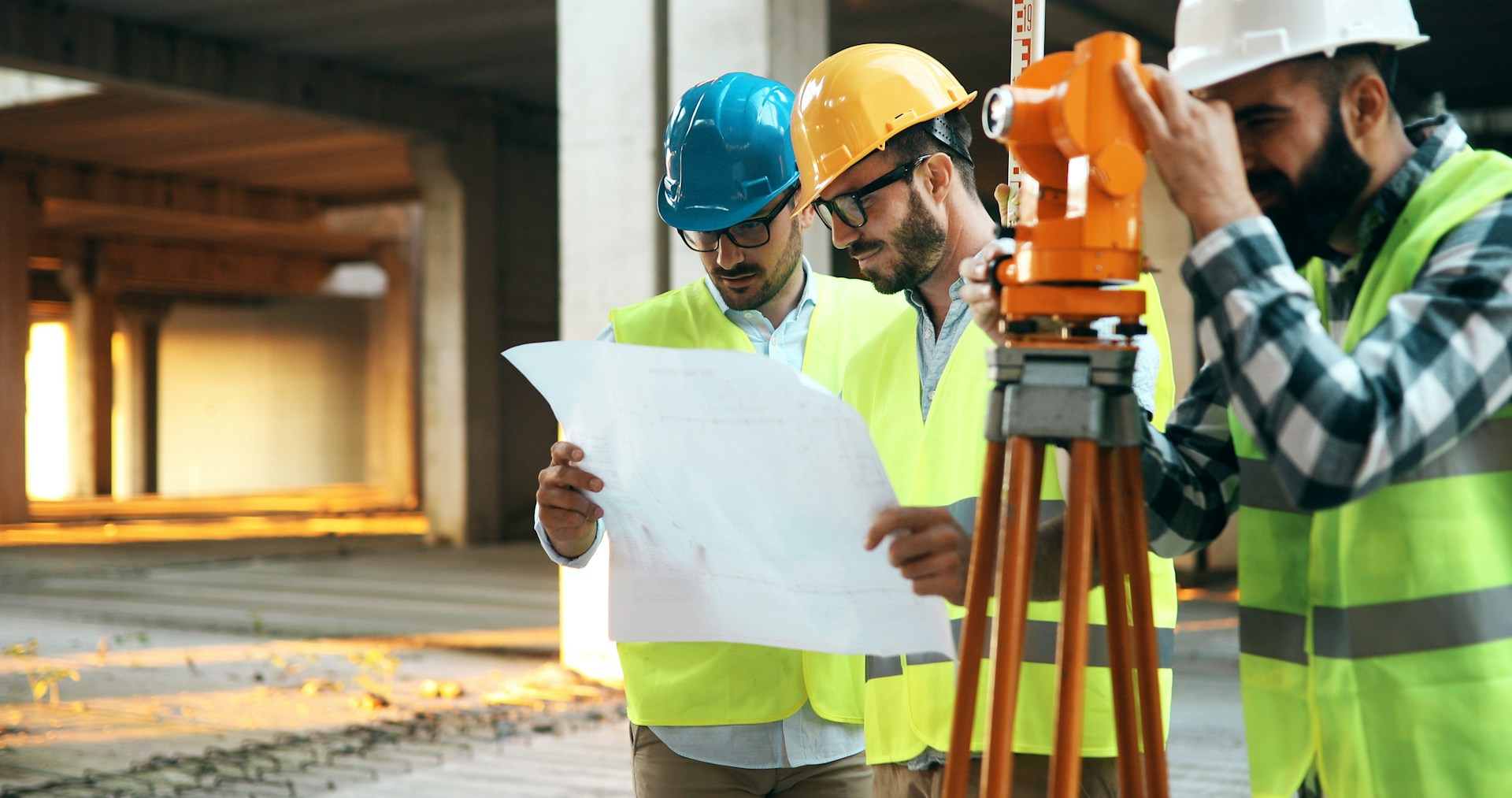 Land surveyors on a commercial site looking at blueprints, representing caveat emptor and commercial real estate deals