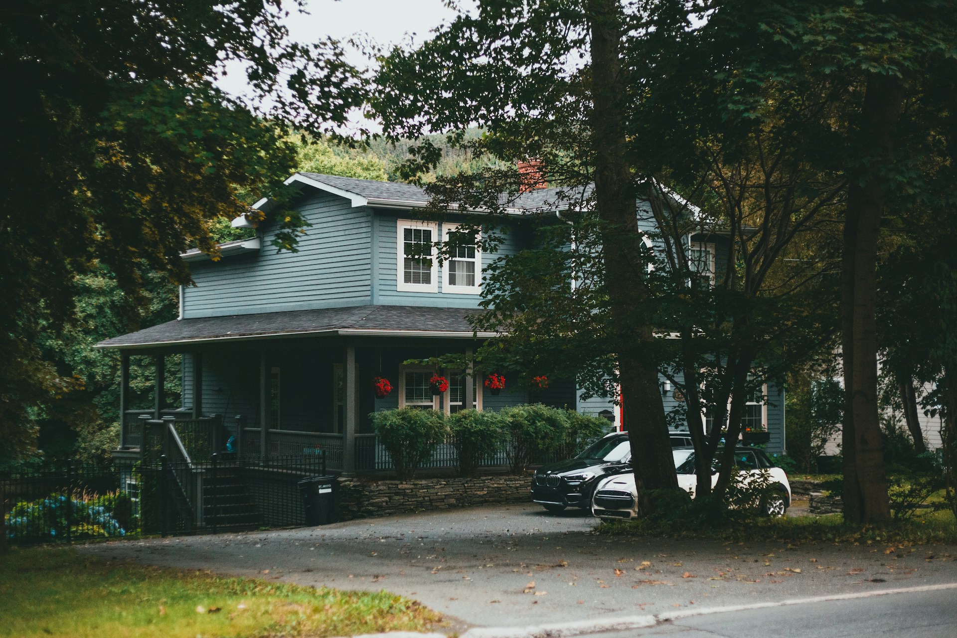 A blue multi-level house in a lush green neighbourhood, representing Contracts of Purchase and Sale in B.C. real estate transactions