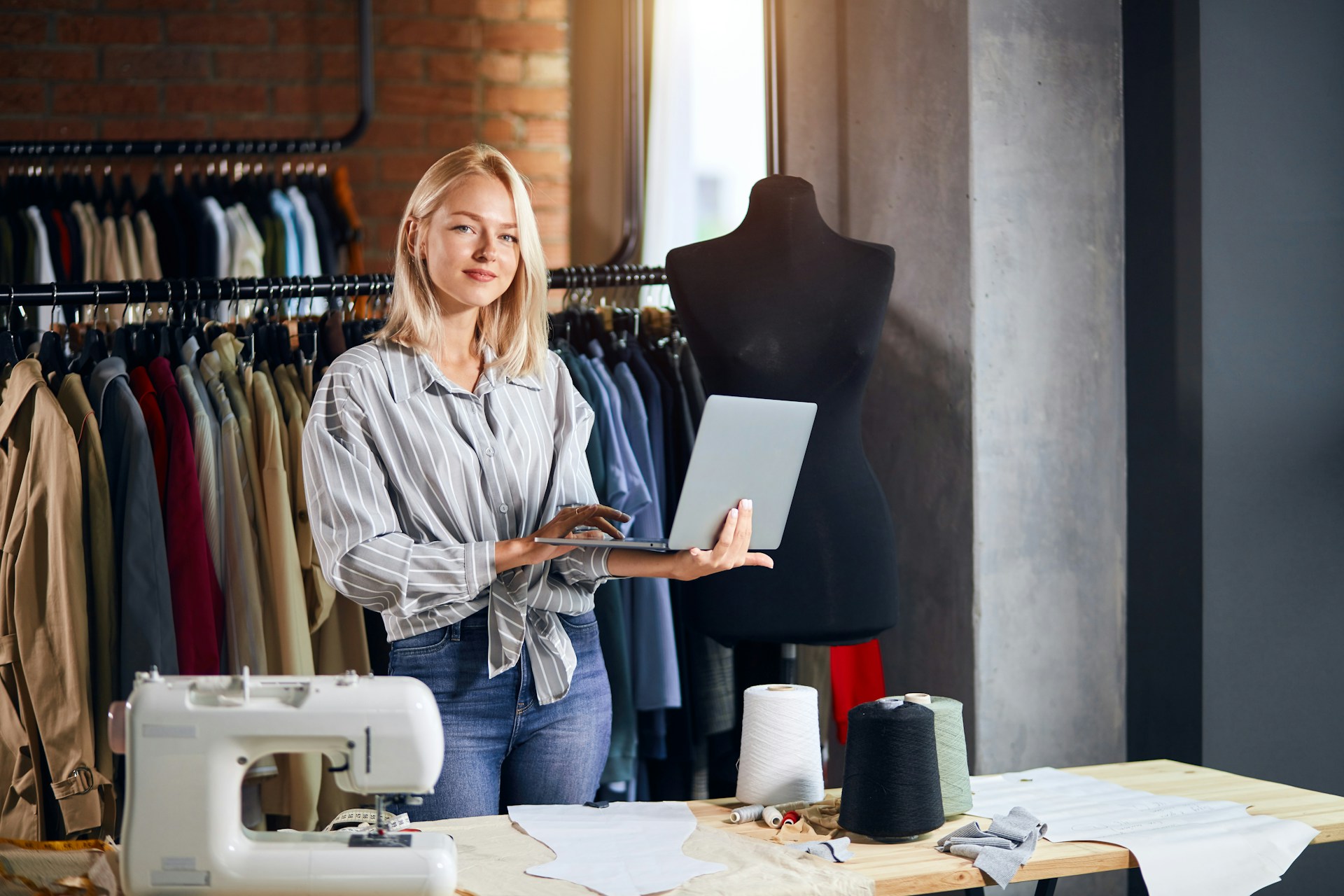 A young female entrepreneur of a fashion boutique holding a laptop, representing British Columbia SMEs and the essential agreements businesses should have