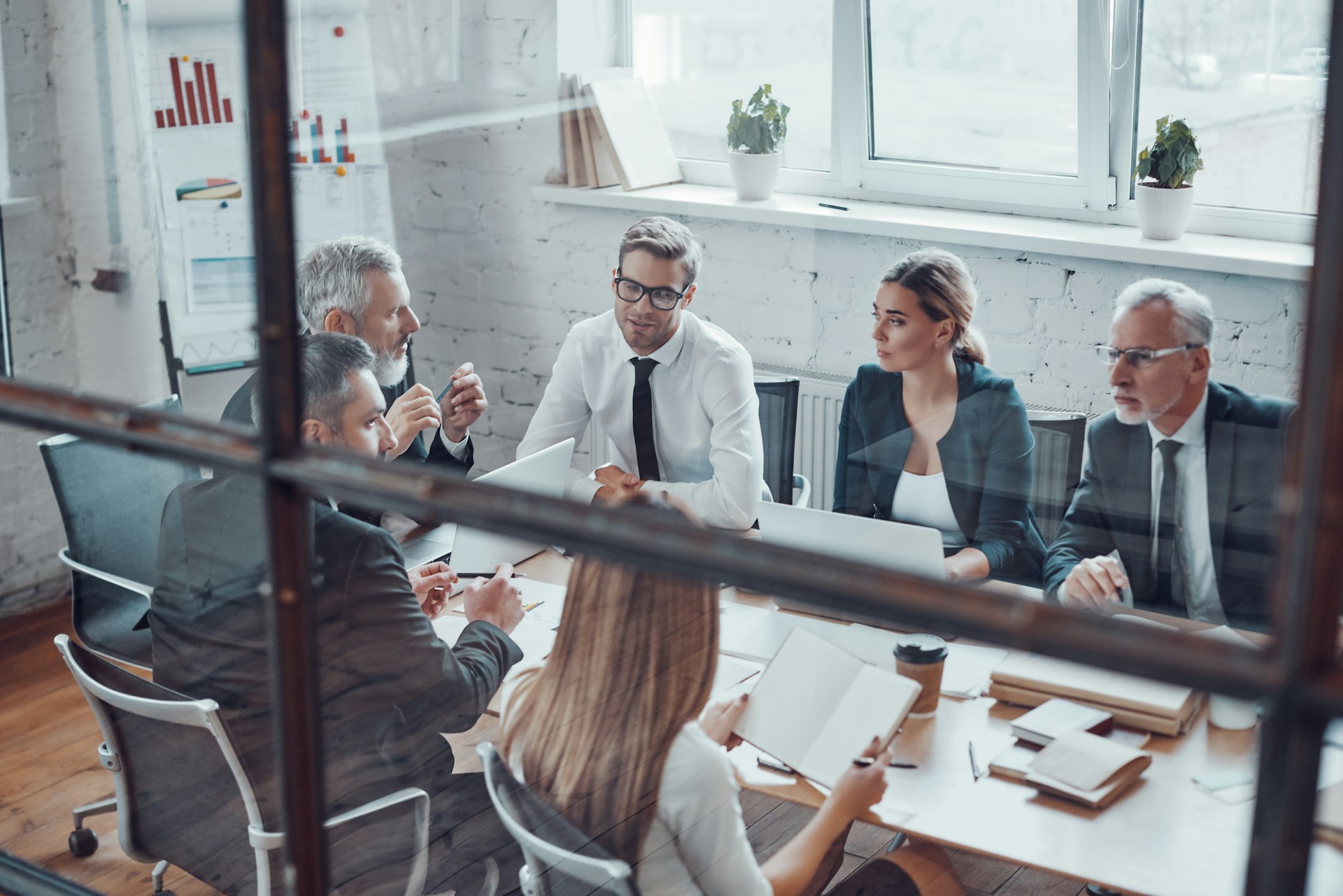 Shareholders meet around a conference table behind the glass boardroom wall, representing shareholder oppression in BC.